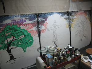 Digital photo of an early in-progress shot of 3 acrylic paintings comprising the "3 Trees Triptych": respectively entitled "Rebellion: The Tree of Knowledge of Good and Evil", "Redemption: The Tree of the Cross" and "Reunion: The Tree of Life", all are © 2017 (Linda) "Eilee" S. George, 48"w x 60"h each, part of the Israel Series for Calvary Community Baptist Church in Northglenn, CO; lovingly painted with squarish strokes in a Neo-Pixelist style in many colors; each signed L. Eilee George with logo