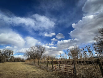 Leading lines galore in clouds, fence, and mowing lines by a Colorado farm © 2022 L. Eilee S. George
