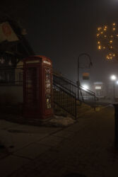 Old British style phone booth ornamenting Olde Town Arvada during a foggy night © 2022 L. Eilee S. George