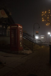 Old British style phone booth ornamenting Olde Town Arvada during a foggy night © 2022 L. Eilee S. George